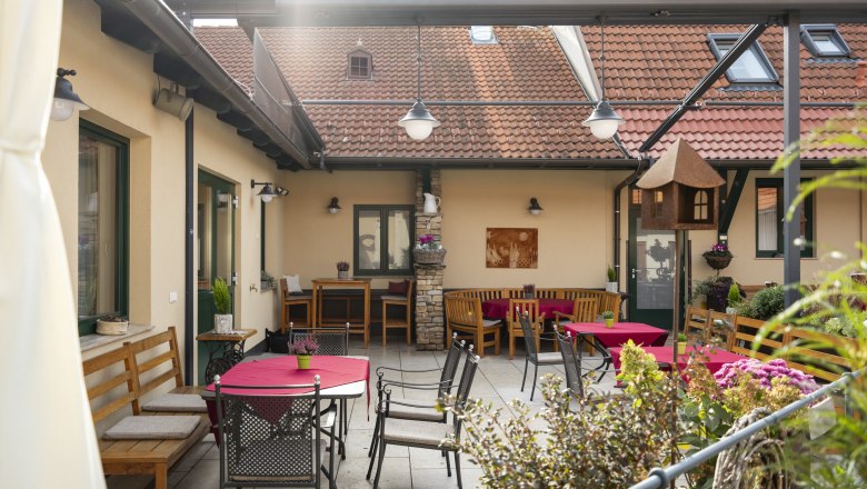 Cozy inner courtyard with seating and red tablecloths.