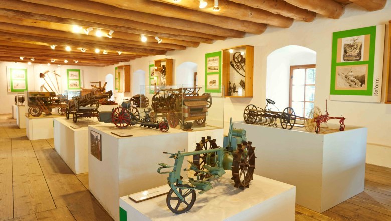 Interior view of the Leiben Agricultural Engineering Museum with historical agricultural equipment on pedestals.