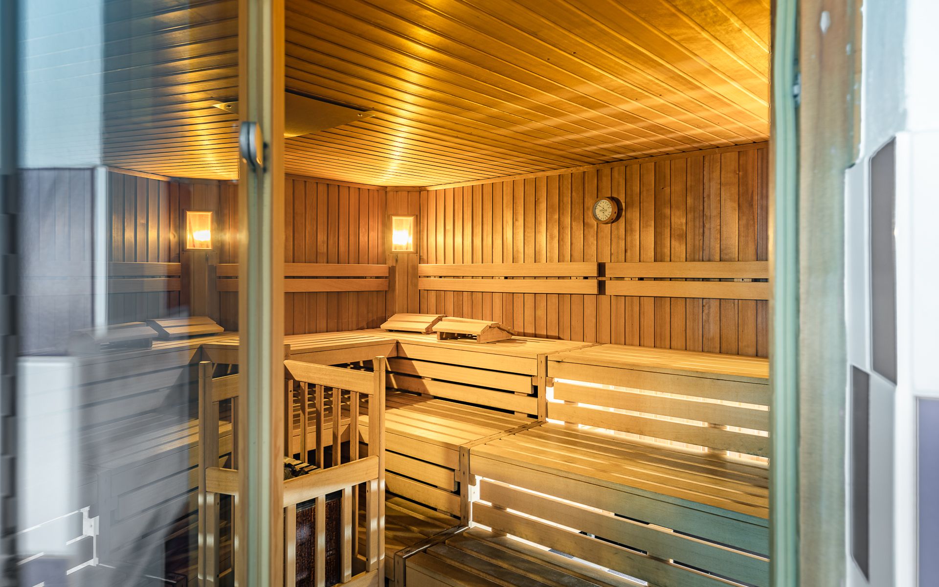 Interior view of an empty sauna with wooden benches and wall clock.