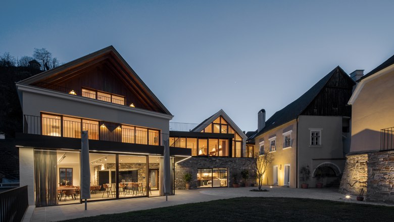 Modern building of the Mauritiushof with large windows at dusk, illuminated by warm light.