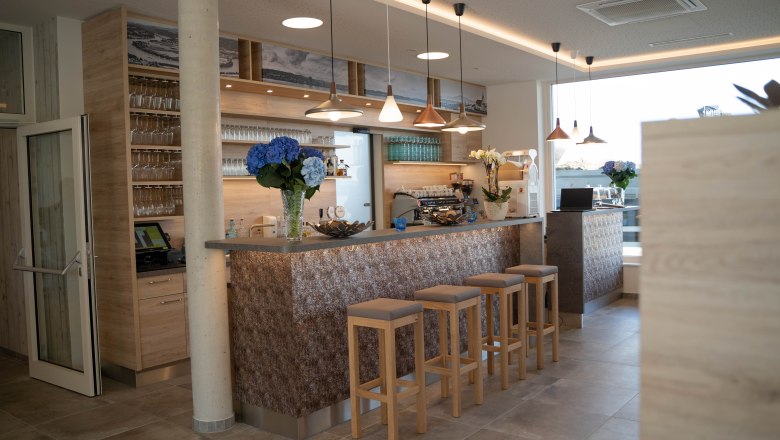 Modern bar with wooden decor, bar stools and flowers.