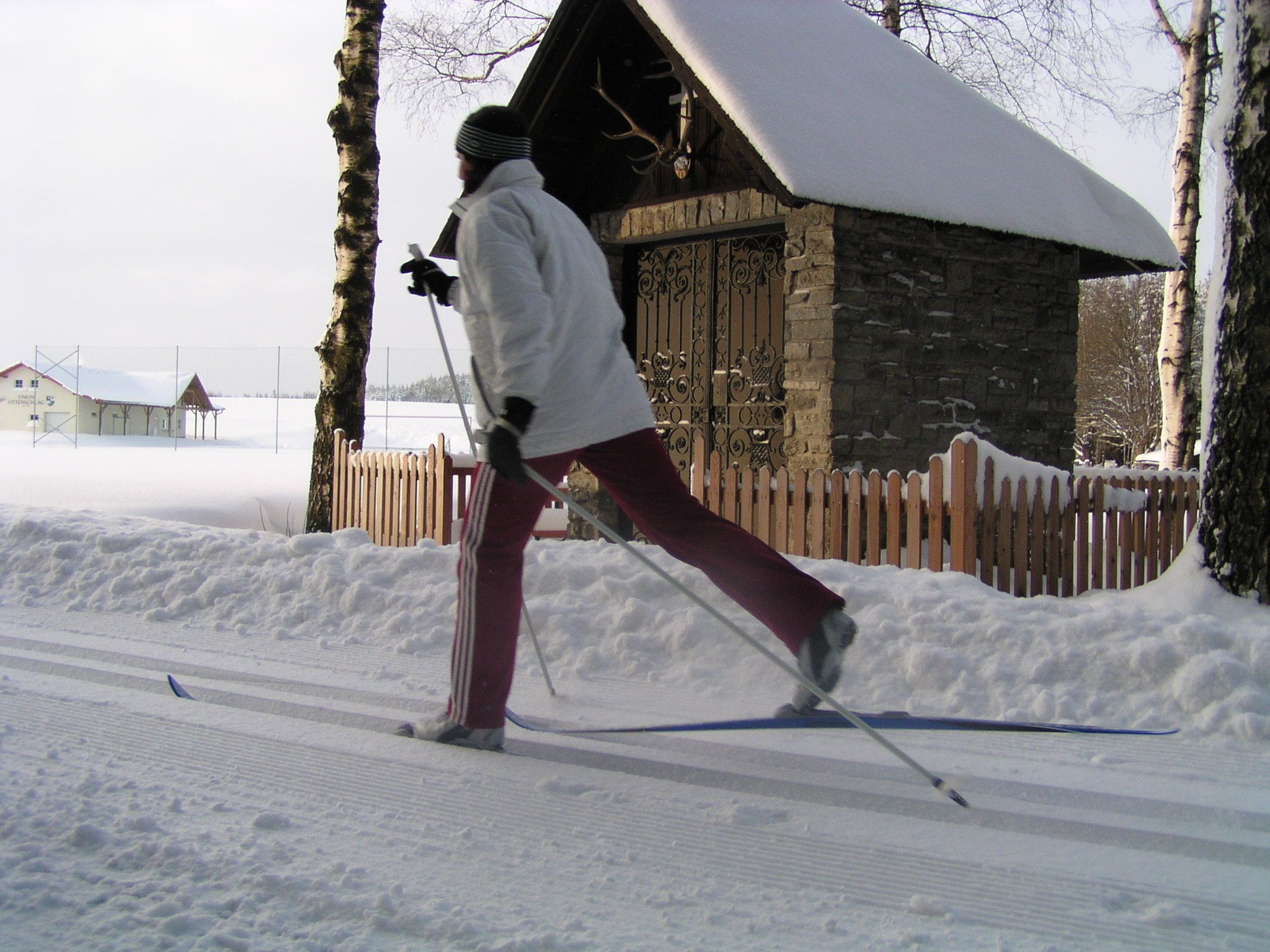 Person cross-country skiing in front of a snow-covered chapel.