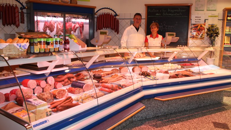 Two people behind a meat counter in a butcher's shop.