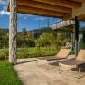 Terrace of a vacation home with two sun loungers, surrounded by green landscape and trees.