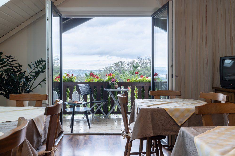 Breakfast room with wooden furniture and view of a balcony with flowers.