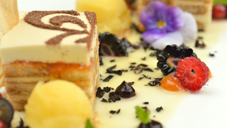 Close-up of an artfully arranged dessert with tiramisu, berries and edible flowers.