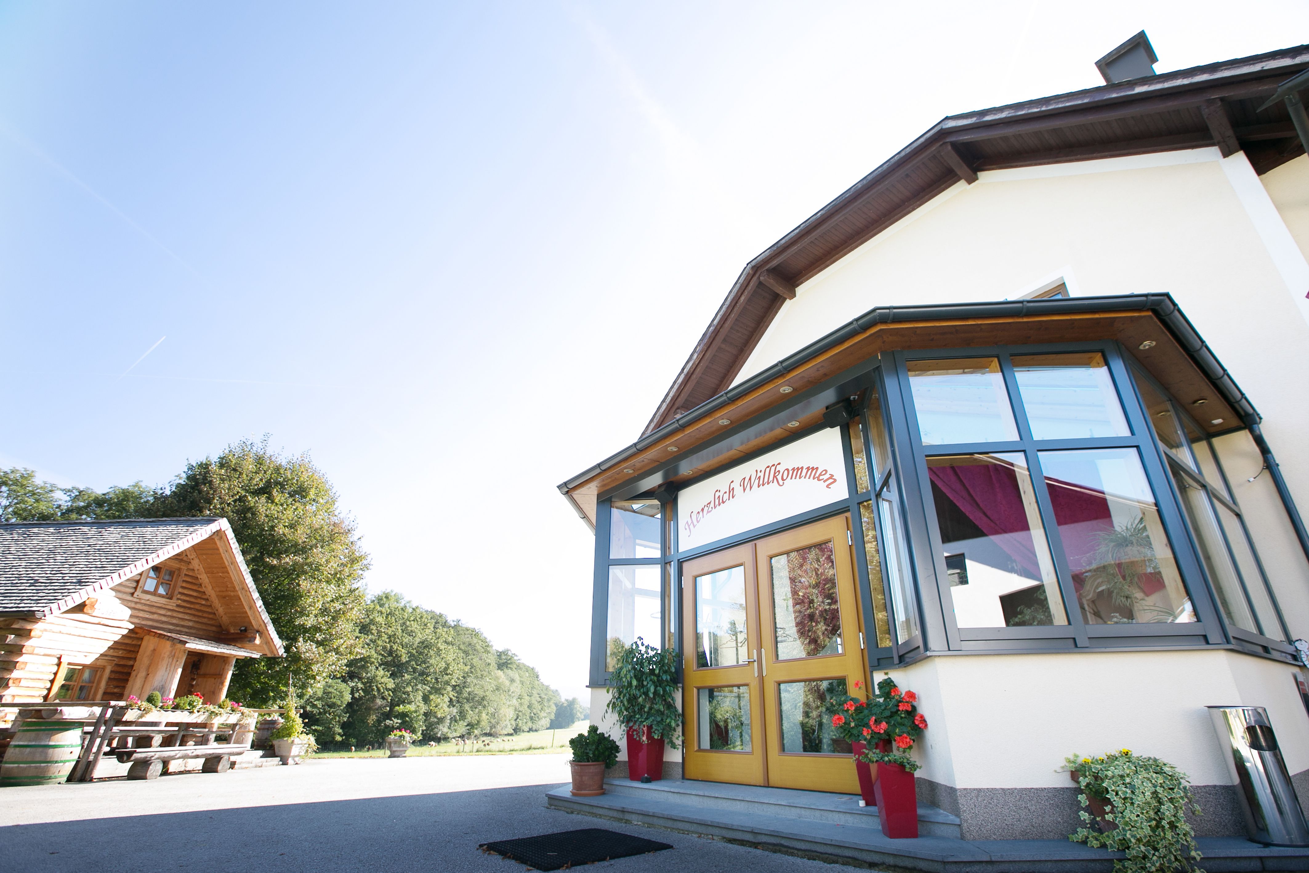 Entrance to a building with glass veranda and "Welcome" sign.