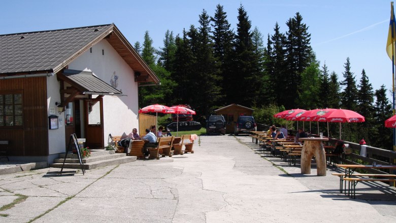 Outdoor area of the Pollereshütte with seating and parasols.