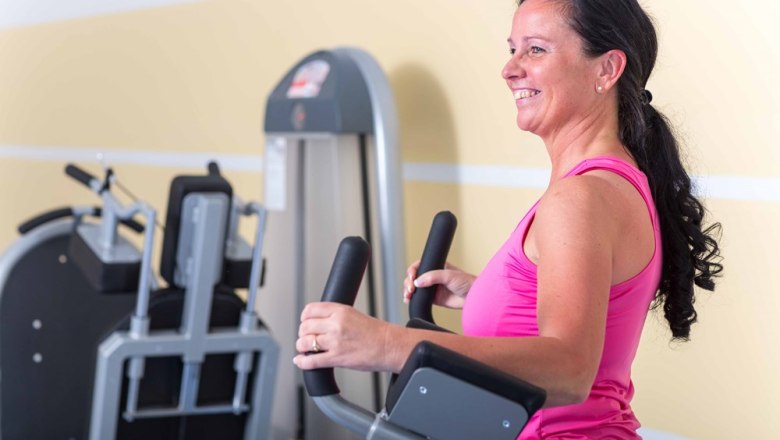 Woman exercising on a cross trainer in the gym.