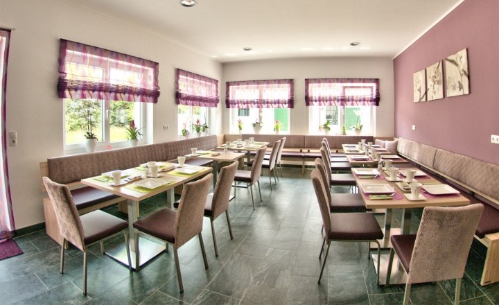 A modern dining room with laid tables, purple curtains and wall decorations.