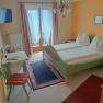 Room with green double bed and table with chair