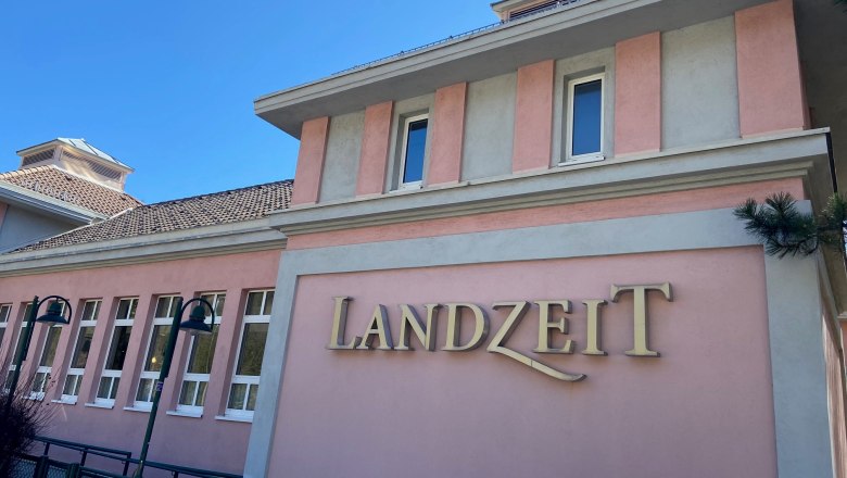Building with a pink façade and the lettering 'Landzeit'.