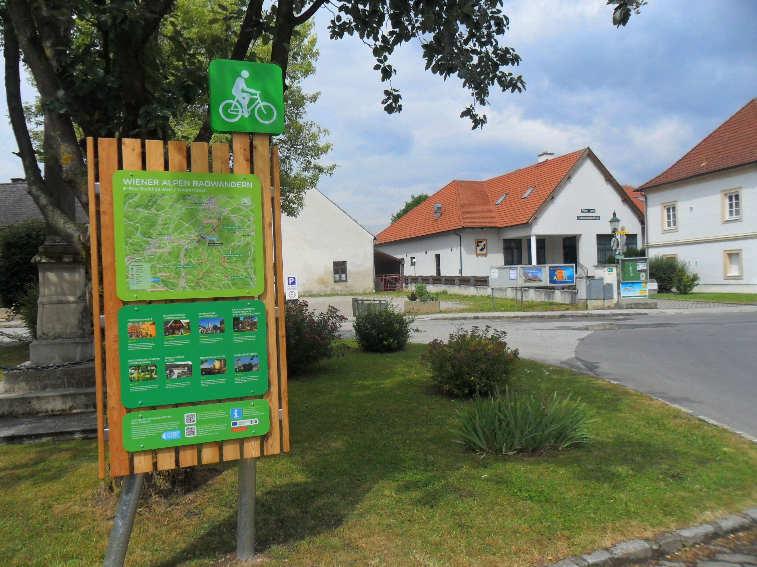 Cycle starting point board in Walpersbach with map and information, surrounded by buildings and trees.