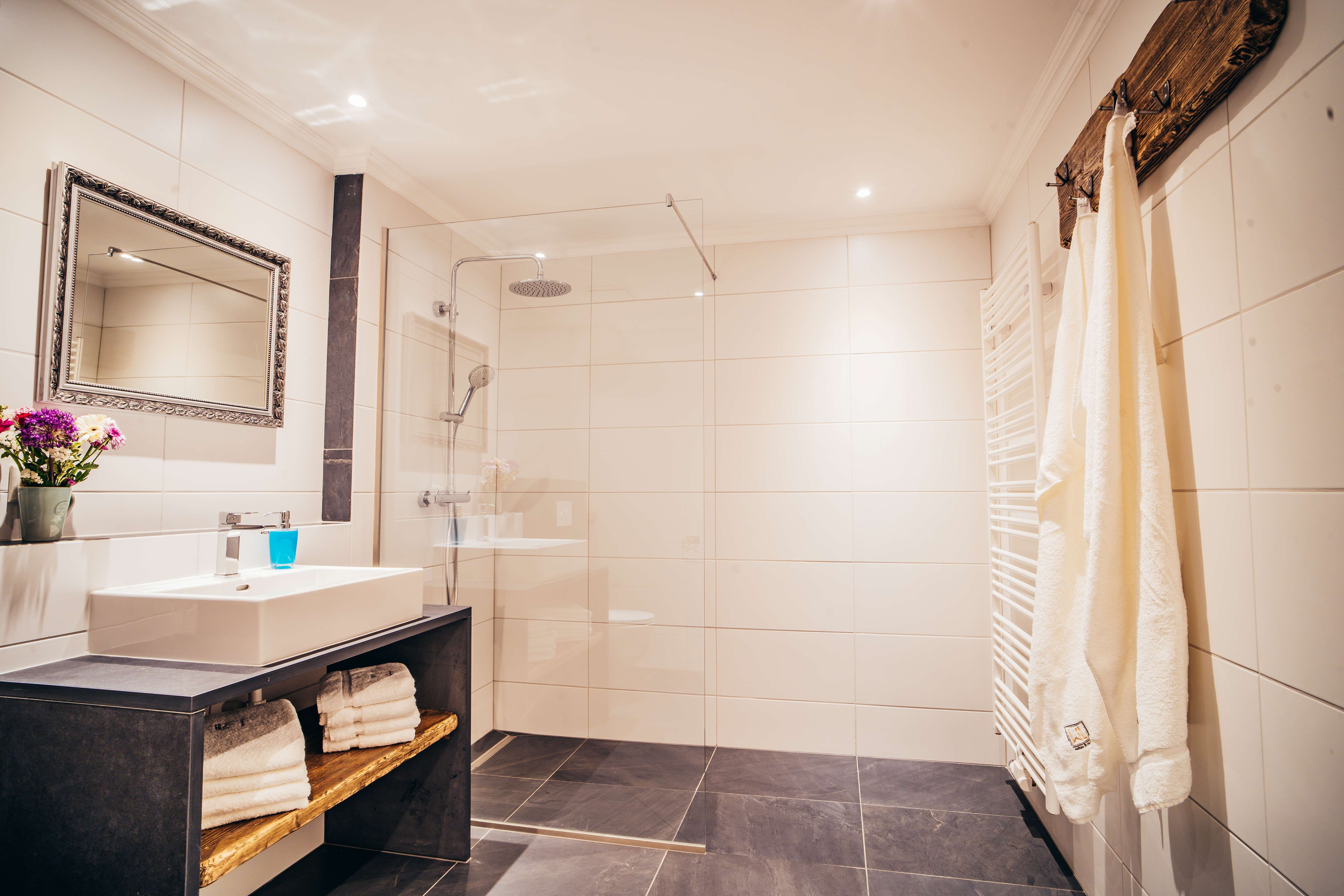 Modern bathroom with large shower, washbasin, mirror and towels.