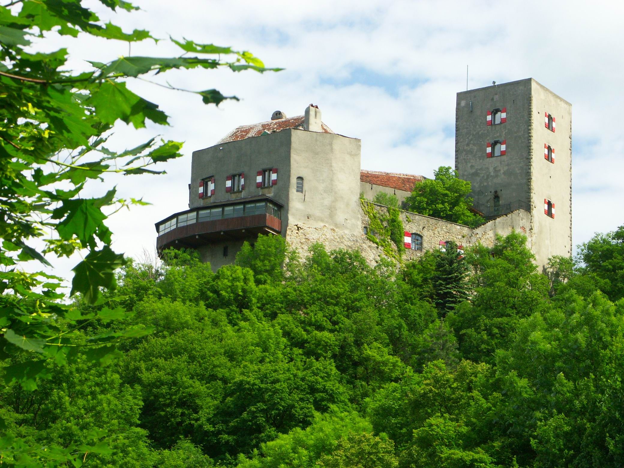Greifenstein Castle on a wooded hill with a blue sky in the background.
