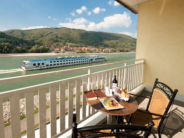 Balcony with table, wine and snacks, view of the river and passing ship.