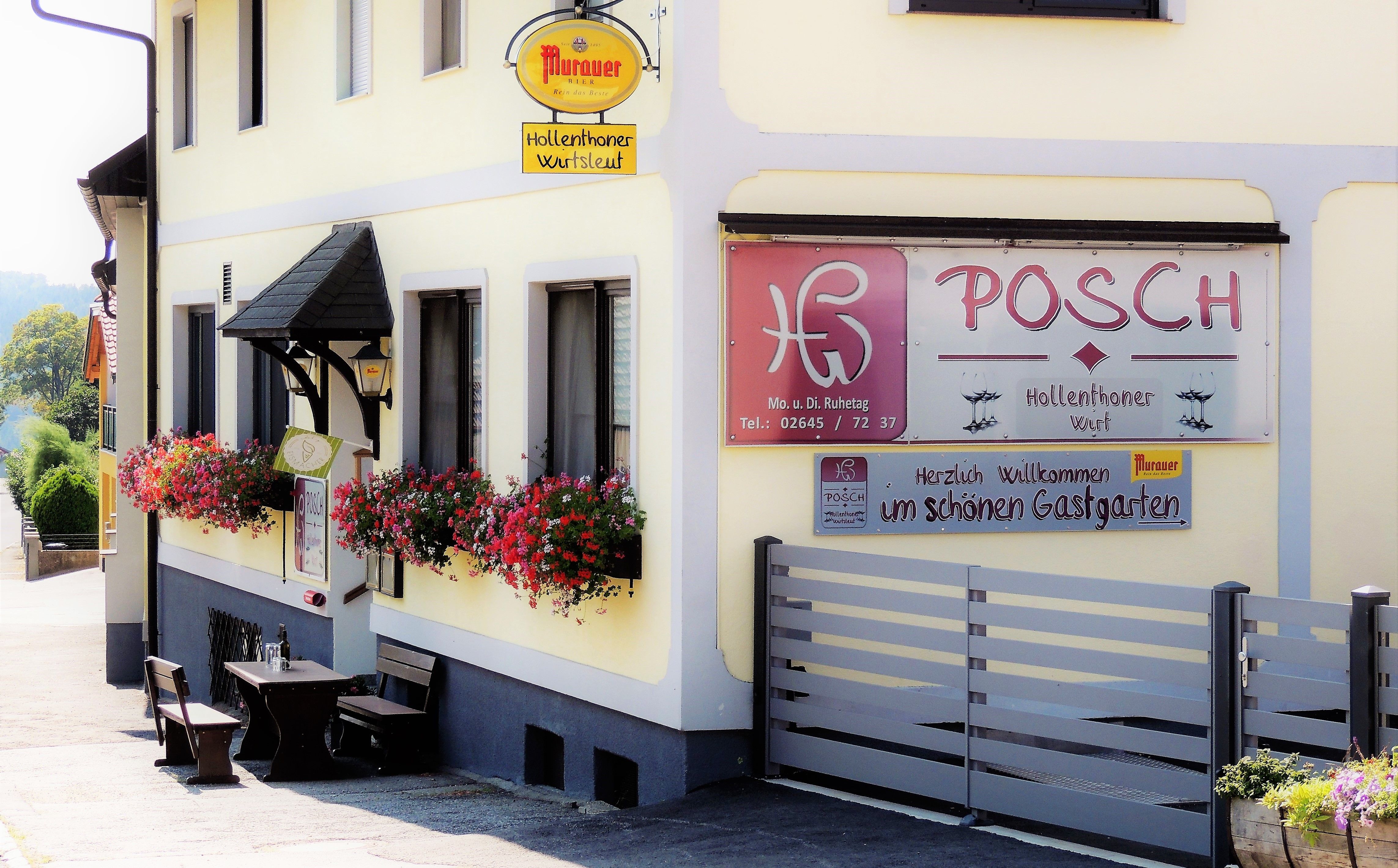 Exterior view of Gasthaus Posch with flowers and seating.
