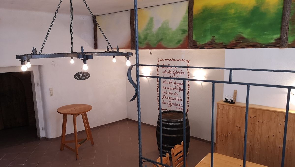 Interior view of a rustic cellar with wooden table, wine barrel and wall decoration.