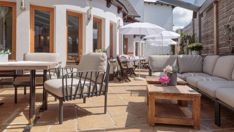 Modern terrace with comfortable seating, wooden tables and parasols.
