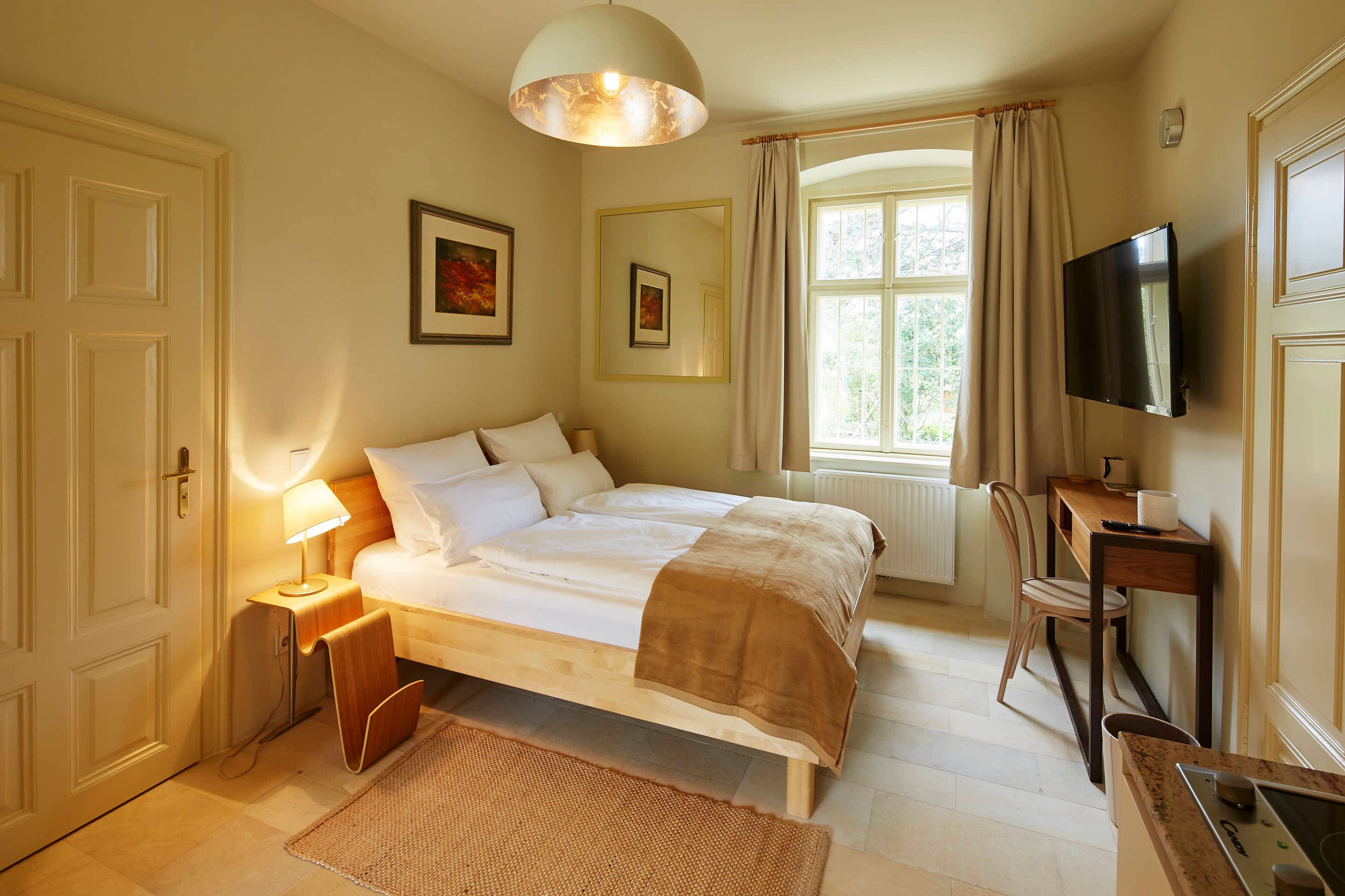 Comfortable bedroom with double bed, desk and large window.