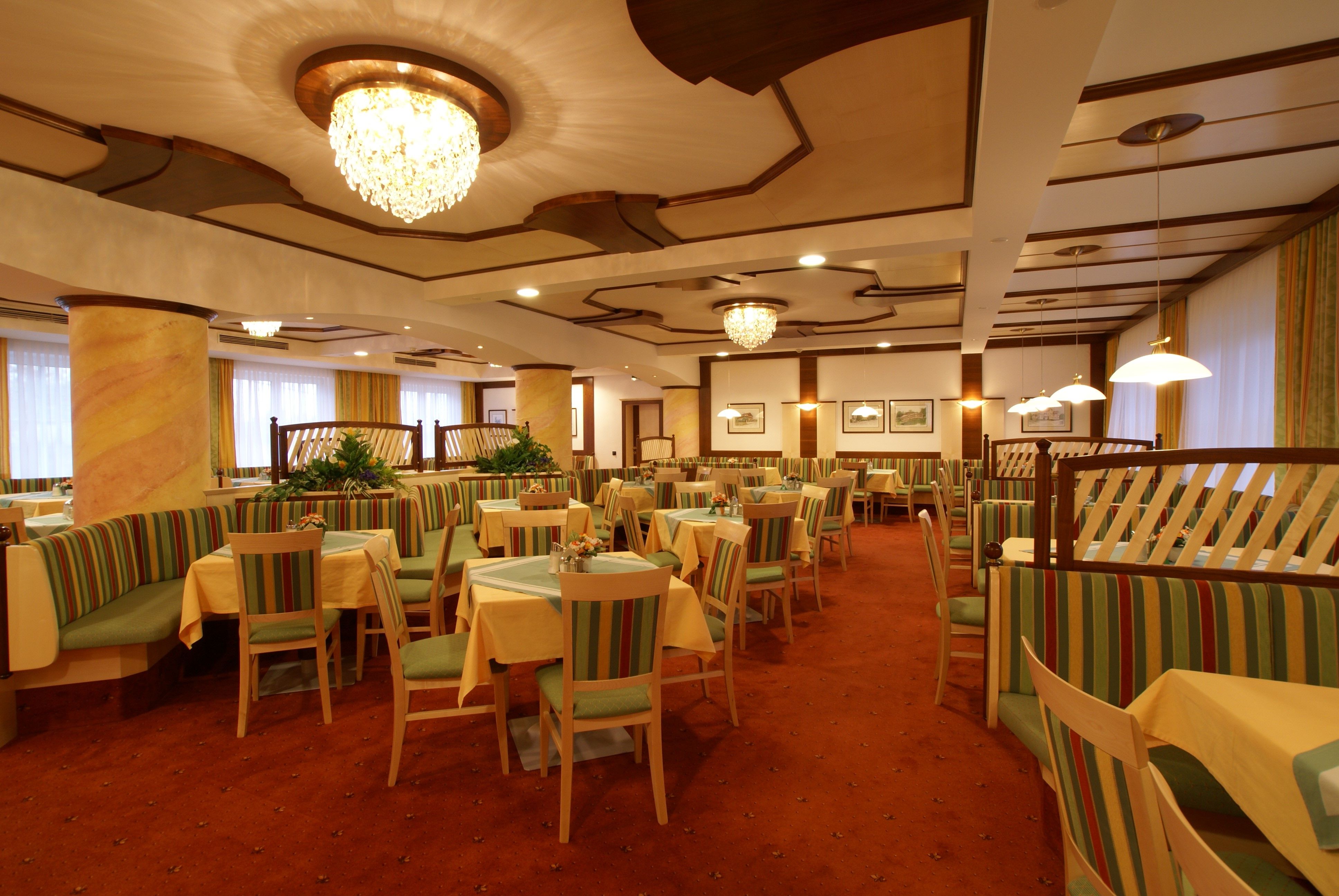 Elegant dining room with chandeliers and striped upholstered furniture.