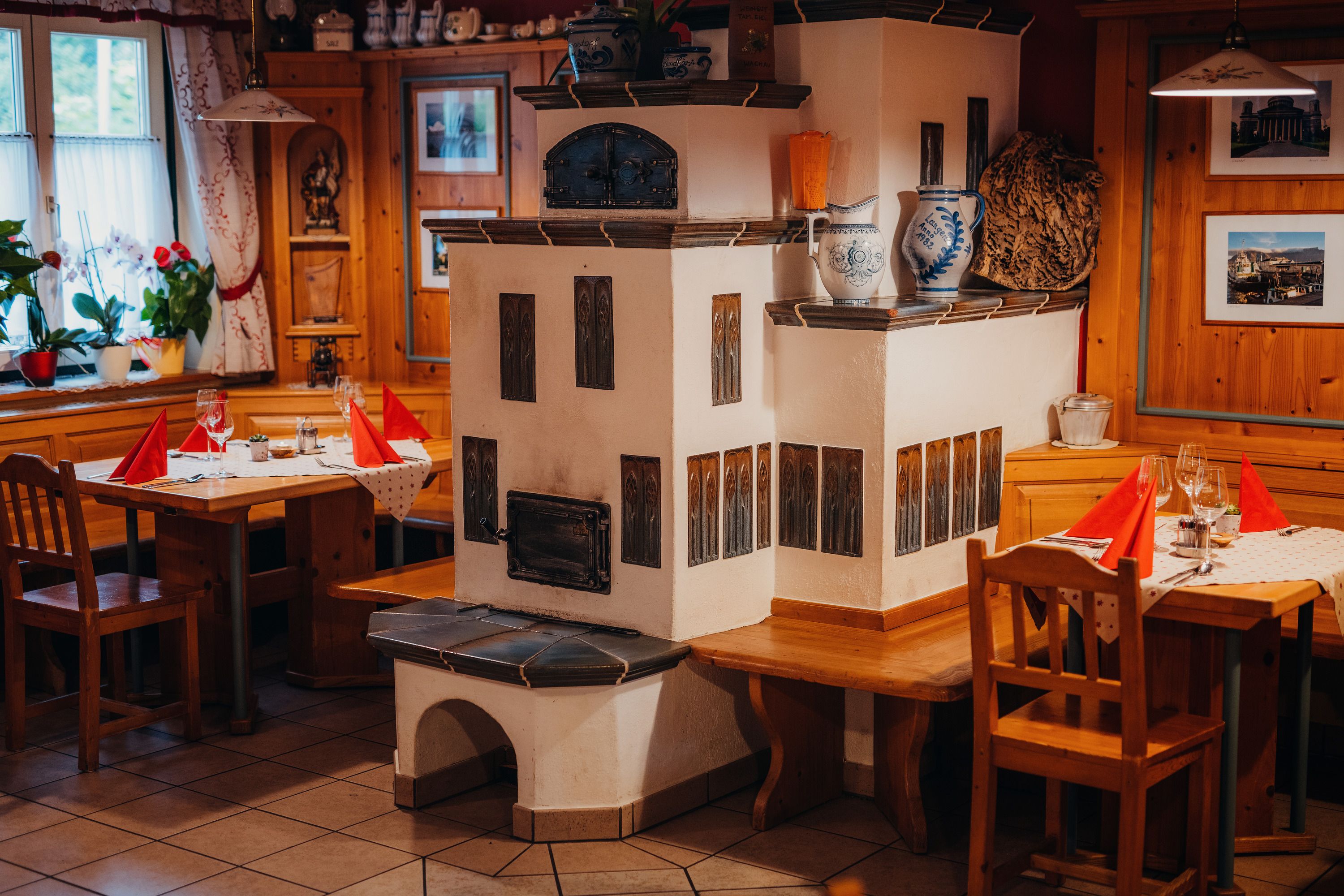 Cozy parlor with tiled stove, wooden furniture and laid tables.