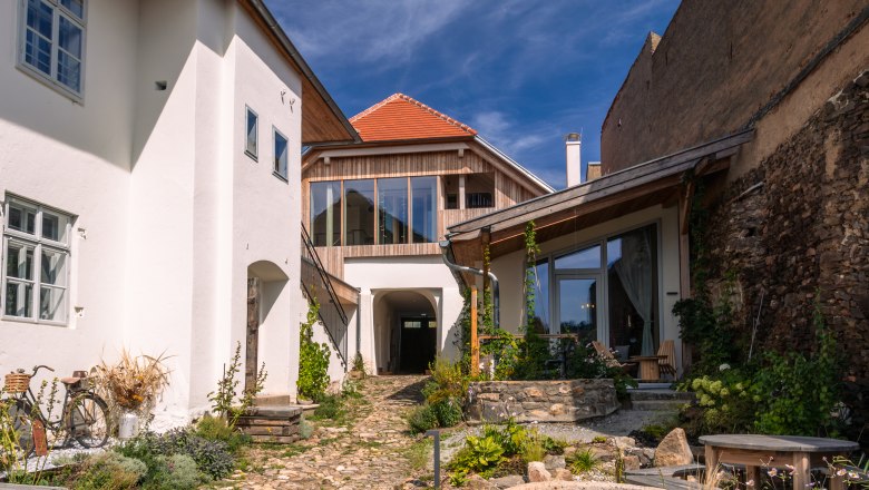 Inner courtyard with paved path, plants and modern buildings under a blue sky.
