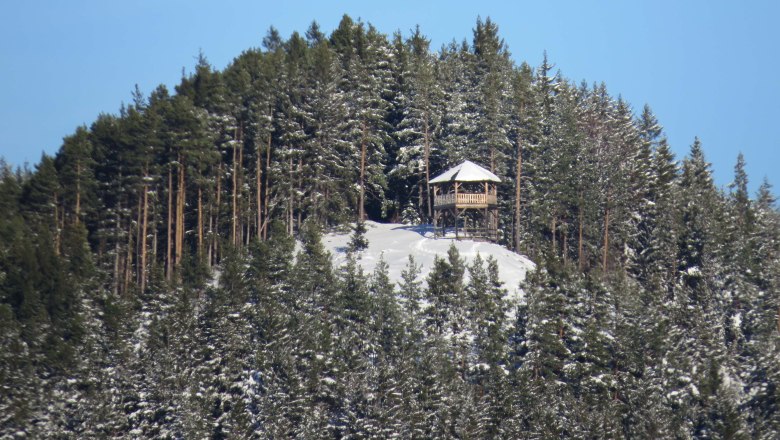 Snow-covered Kernstockwarte on a wooded hill.