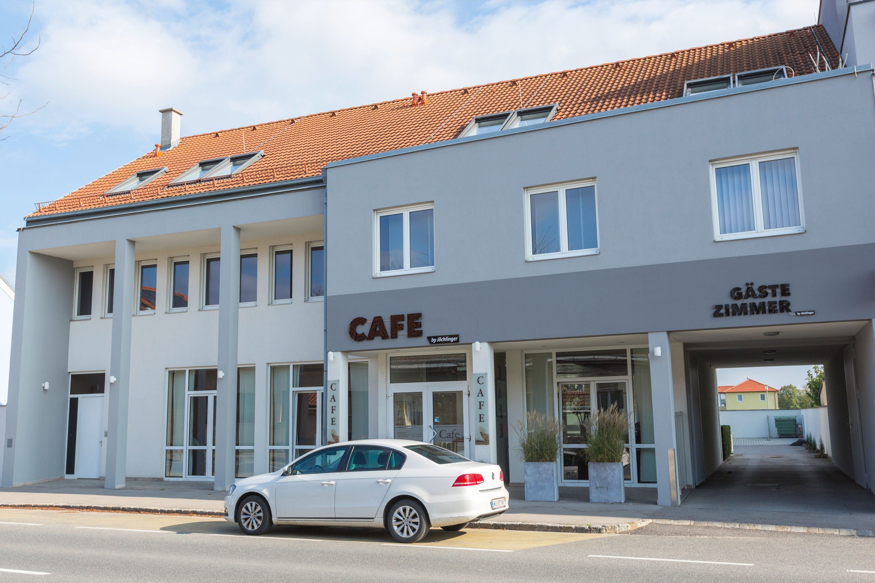 Exterior view of a gray building with a café and guest rooms.