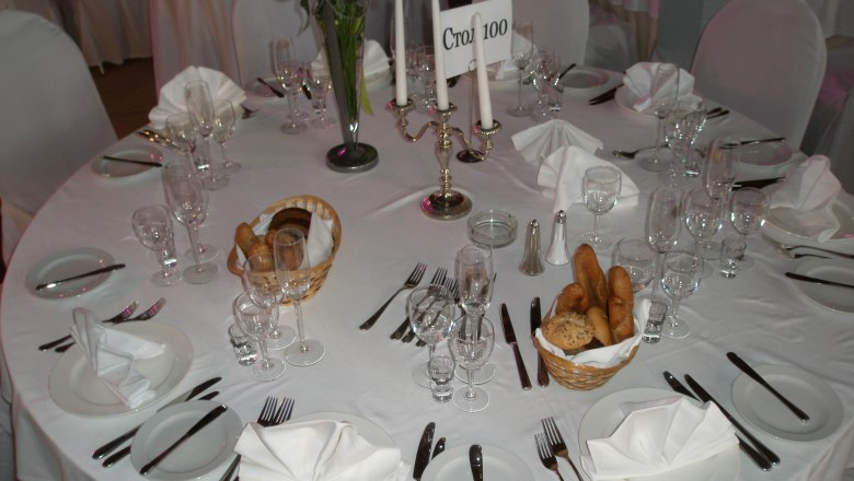 Elegant table setting with white tablecloths, candlesticks and bread baskets.