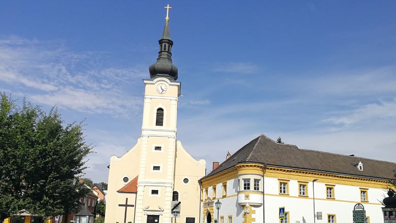 Parish church with tower and adjoining vicarage under a clear sky.