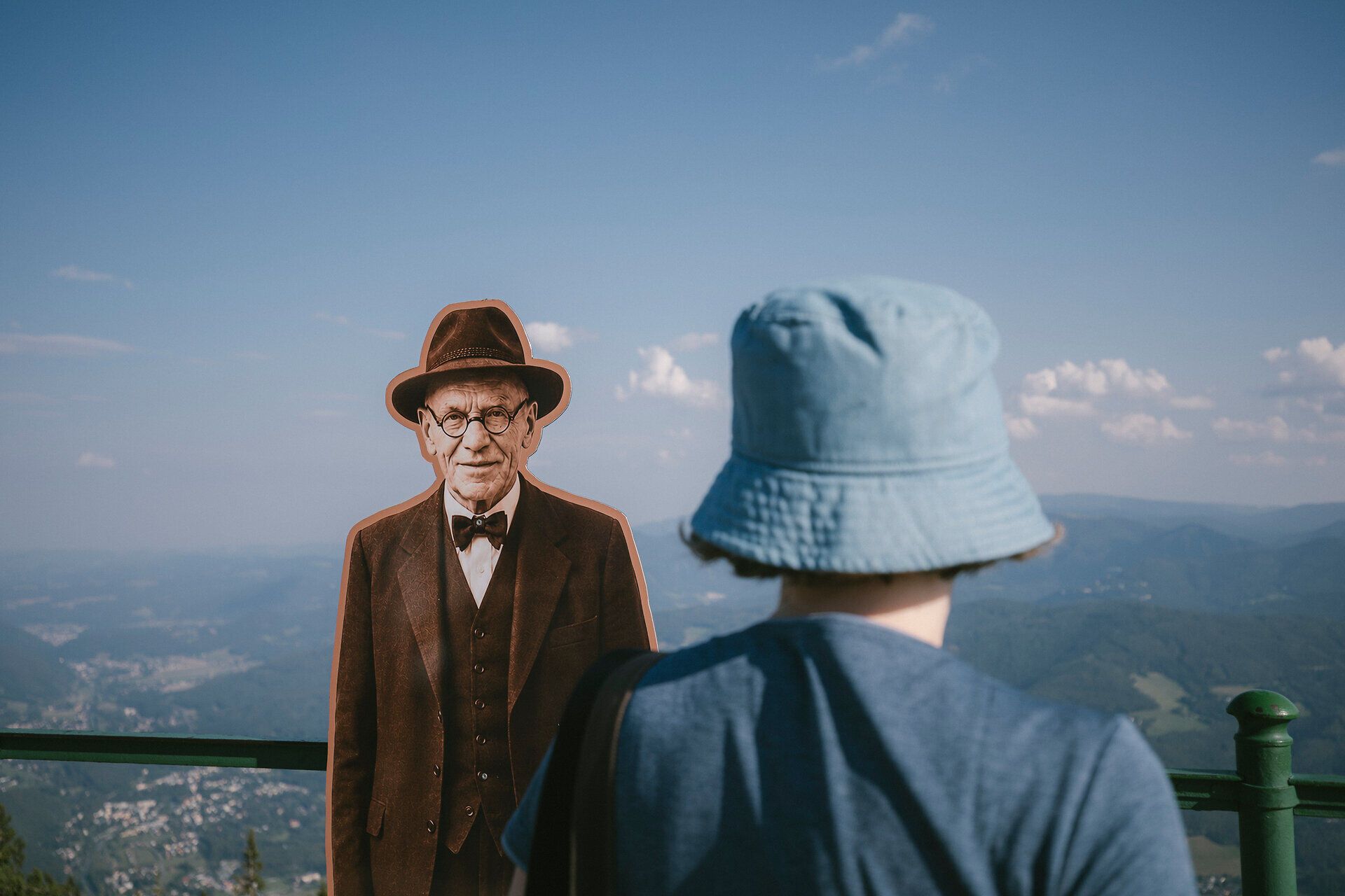 A child looks at a historical figure displayed as a figurine against a mountain backdrop at the Raxalm mountain inn