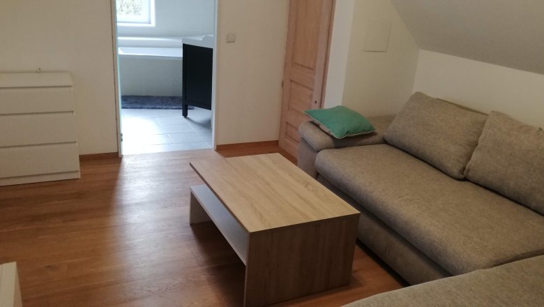 Living room with corner sofa, coffee table and view into the bathroom.
