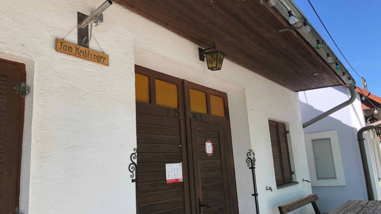 Entrance of a wine tavern with wooden sign 'Fam. Keiblinger'.