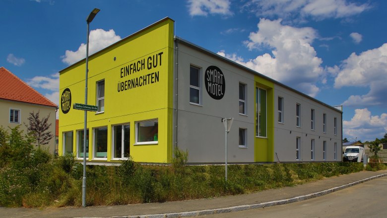 Exterior view of a modern, two-storey motel with a yellow façade and the inscription 'Einfach gut übernachten'.
