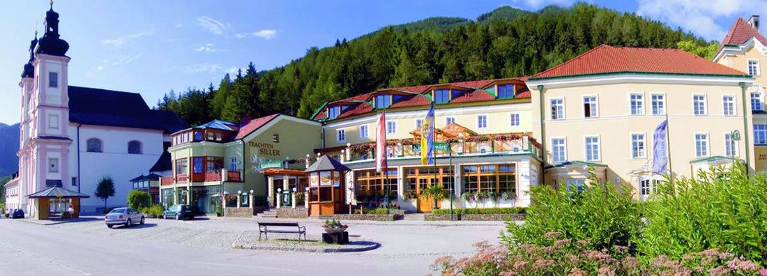 Exterior view of a traditional inn next to a church in a mountainous landscape.