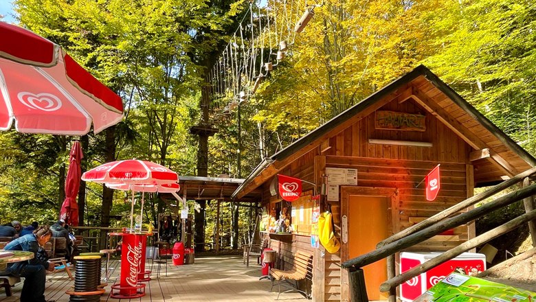 Wooden hut with sunshades and climbing park in the background.