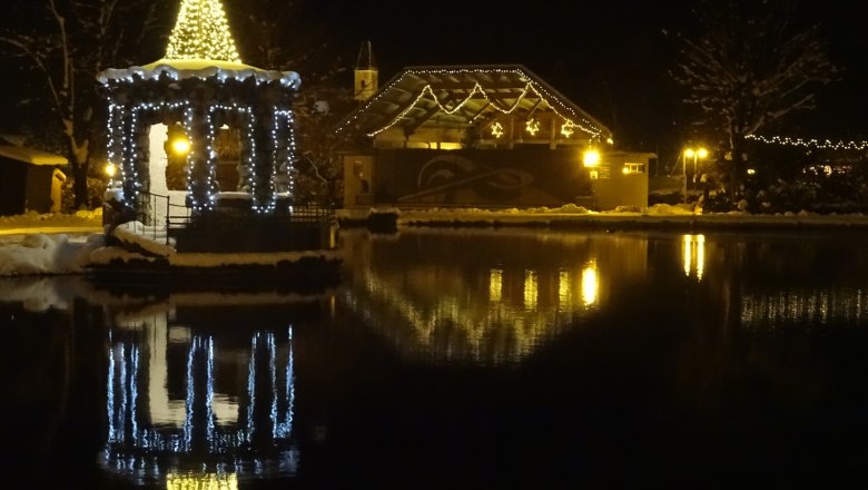 Christmas illuminated pavilion on the lake in Puchberg at night.