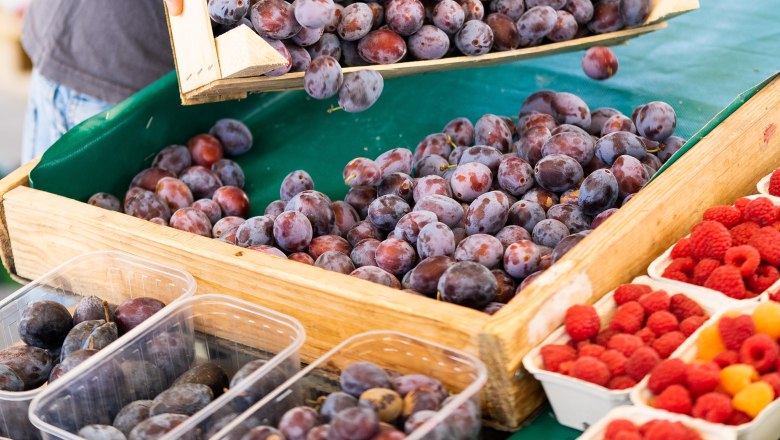 Plums and raspberries on a market stall.