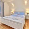 Bright bedroom with double bed, wooden floor and two bedside tables with lamps.
