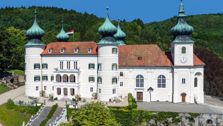 Artstetten Castle with towers and gardens against a wooded background.