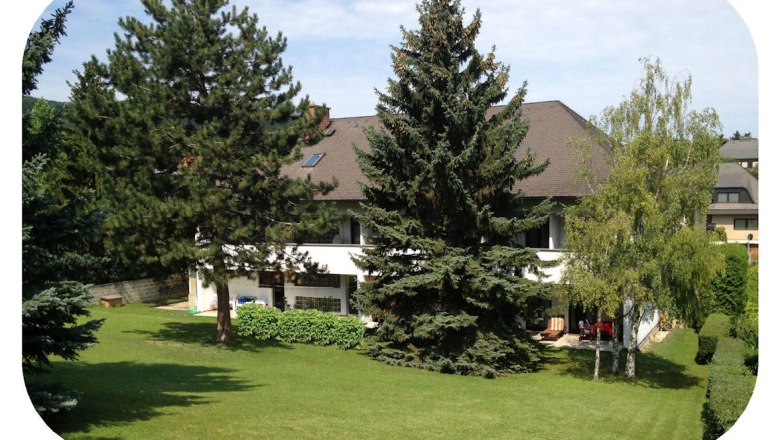 Rear view of an inn with garden and trees.