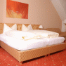 Comfortable hotel room with double bed, wooden furniture and red carpet.