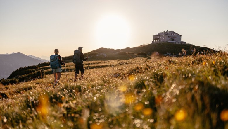 The rolling hills of the Vienna Alps invite you on an unforgettable adventure. Two hikers enjoy the golden evening sun as they stroll through the flowering meadows. The breathtaking views and fresh mountain air create the perfect backdrop for unforgettable memories.