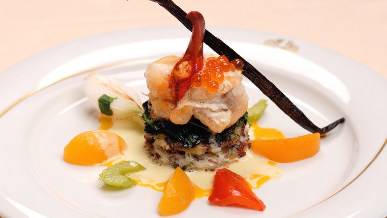 Gourmet dish with fish, caviar and vegetables on a plate.