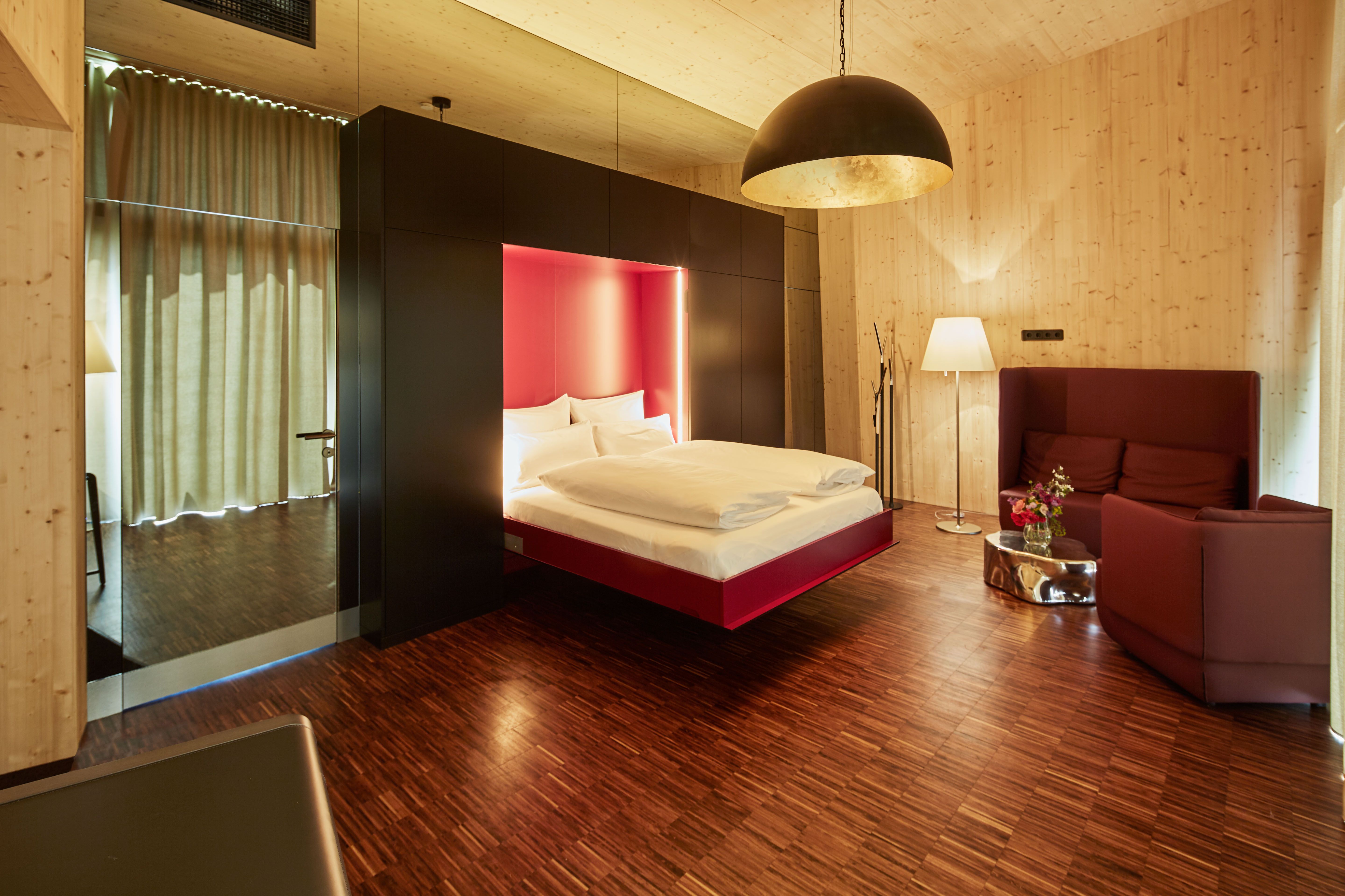 Interior view of a modern bedroom with floating bed, wood paneling and stylish lighting.