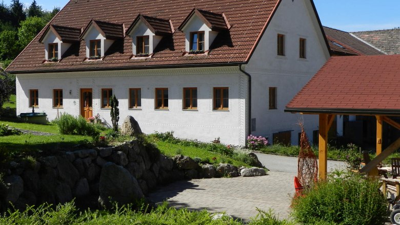 A traditional white country house with a red roof and garden.
