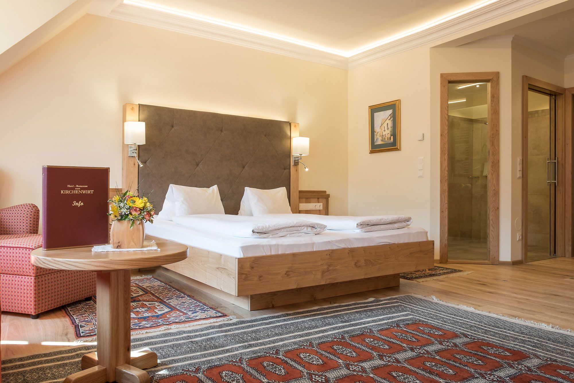 Hotel room with double bed, carpets and wooden furniture.