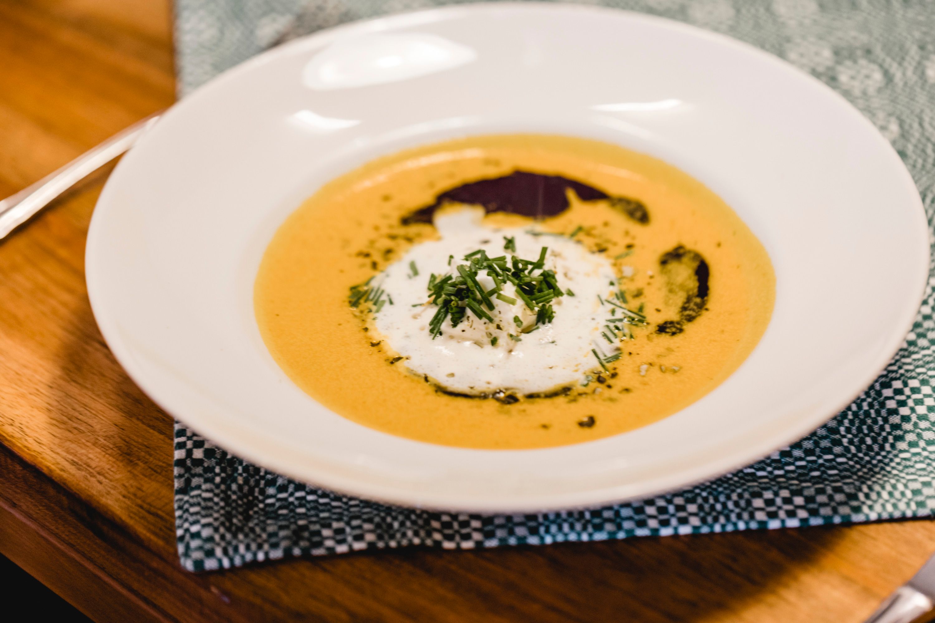 A plate of cream of pumpkin soup garnished with cream and herbs.