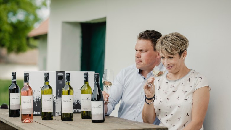 Two people are sitting at a table with bottles of wine and tasting wine.